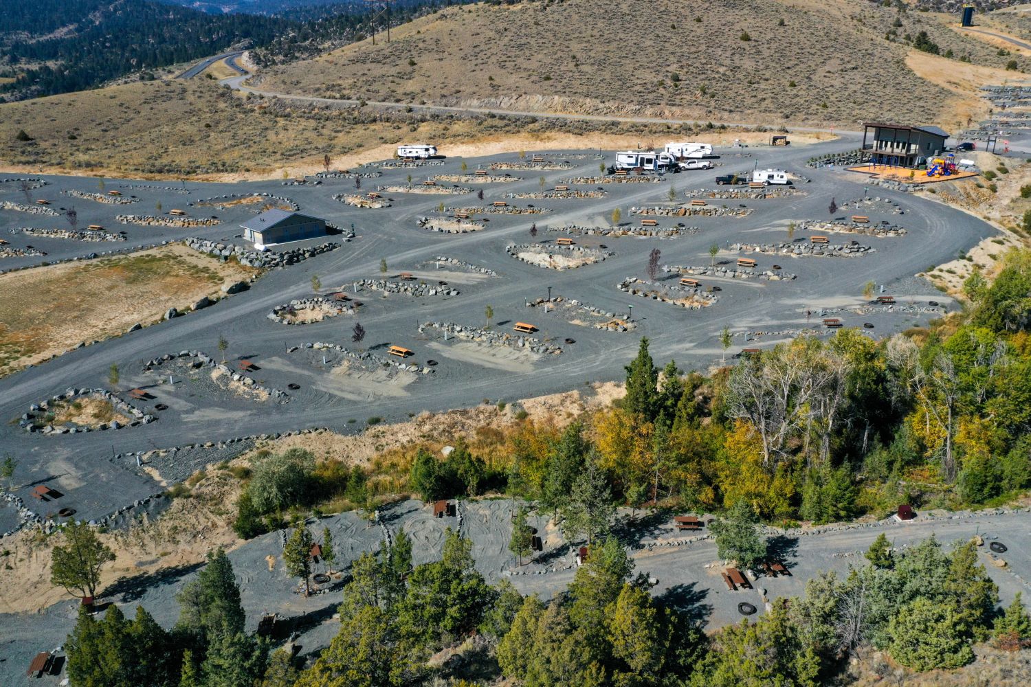 Aerial view of a winding dirt bike or car track with surrounding terrain and RVs parked nearby.